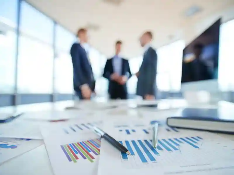 Documents on office table and three men talking in the background